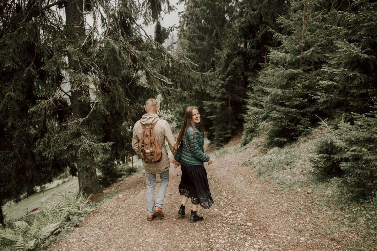 Couple walking hand in hand along a green forest path, preparing for pregnancy together