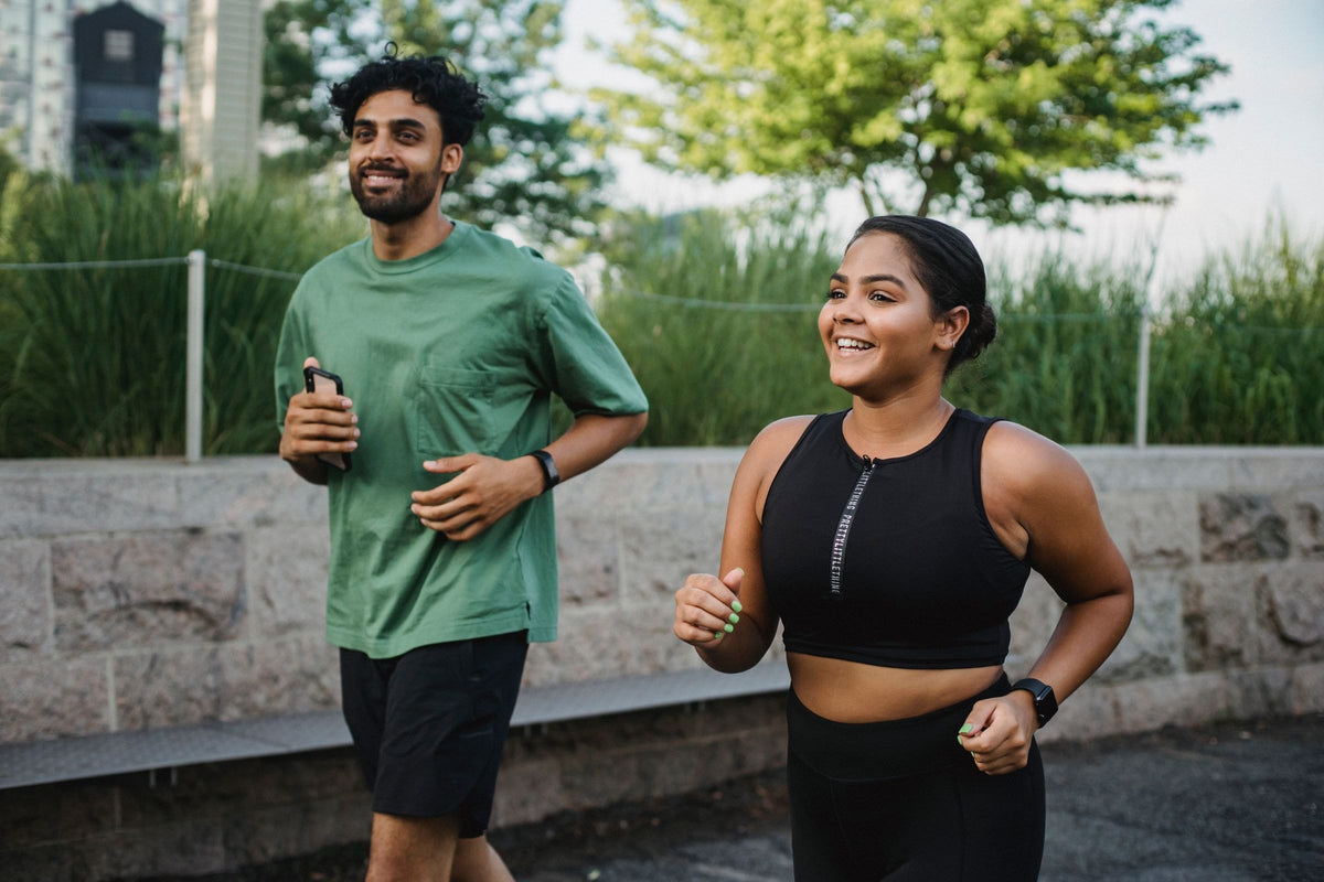 Man and woman jogging together outdoors on a bright day, part of an everyday energy routine