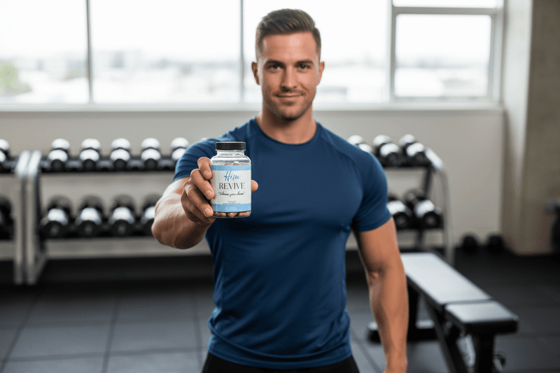 Man in gym holding supplement bottle, weight rack in background, fitness and vitality theme